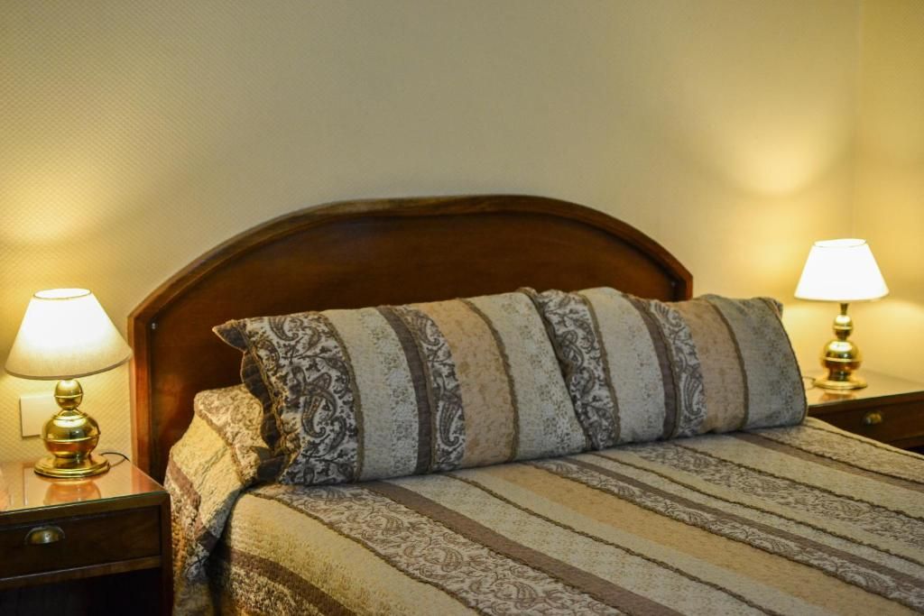 A neatly made bed with patterned bedding and two bedside lamps on wooden nightstands.