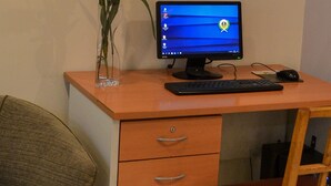A desk with a computer monitor, keyboard, and mouse. There is a vase with flowers on the desk. - Hotel Centro Naval (Buenos Aires)