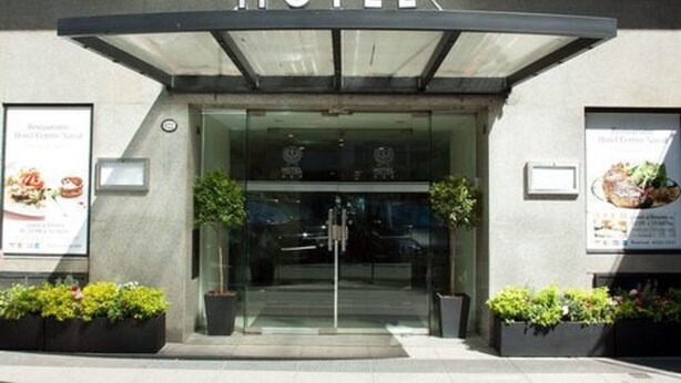 A hotel entrance with a glass door, a sign above reading "HOTEL", and two potted plants on either side. - Hotel Centro Naval (Buenos Aires)