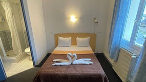 A hotel room with a bed, a shower, and a window with curtains. - Hôtel & Résidence Avermes (Avermes)