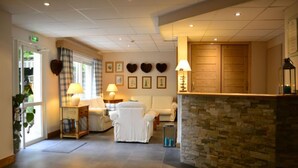 Een hotellobby met een receptiebalie, een zithoek en een stenen muur.