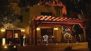 Een terras met een pergola, zitplaatsen buiten en een kleine tafel.