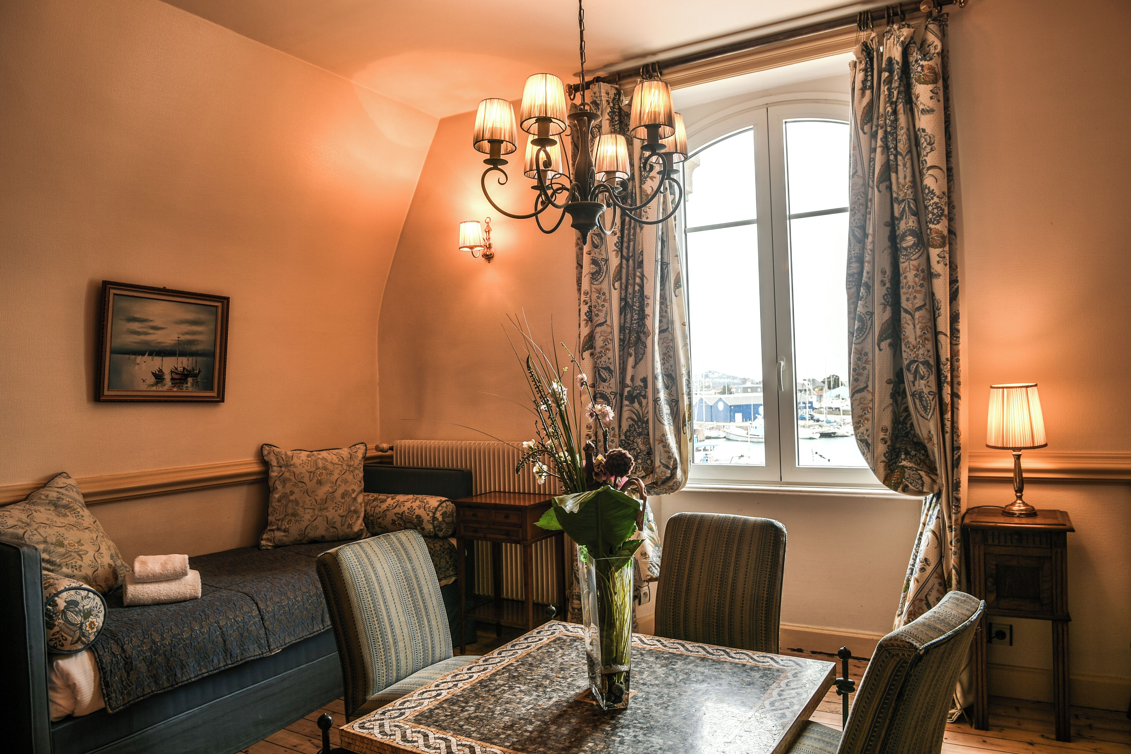 A cozy room with a sofa, a dining table, and a chandelier.