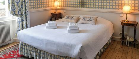 A neatly made bed with white linens, two bedside lamps, and a patterned wall.