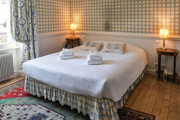 A neatly made bed with white linens, two bedside lamps, and a patterned wall.