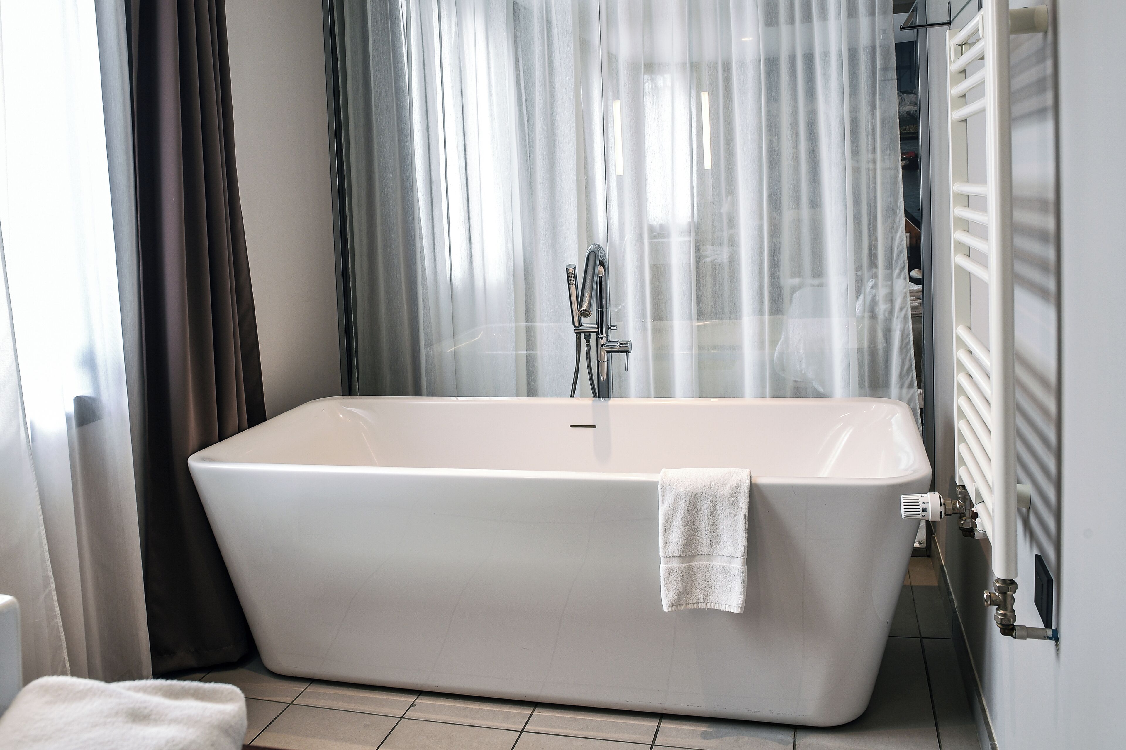 Une salle de bain moderne avec une baignoire sur pieds, une serviette et un espace douche.