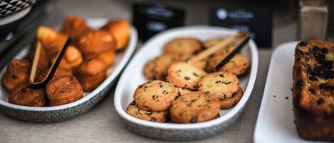 A buffet table with various baked goods including cookies and muffins.