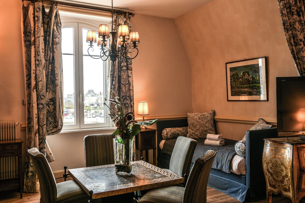 A cozy living room with a dining table, chairs, a chandelier, a sofa, and a television.