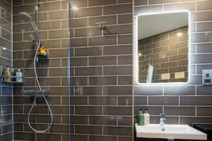 A bathroom with a shower, a sink, and a mirror.