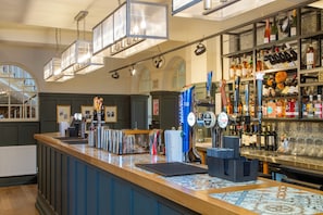 A bar area with a counter, beer taps, and a wine rack.