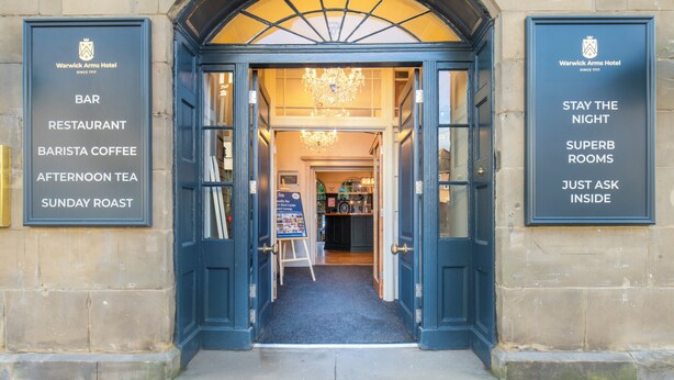 A hotel entrance with signs for the bar, restaurant, barista coffee, afternoon tea, and Sunday roast.