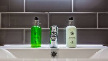 A bathroom sink with three bottles of liquid soap.
