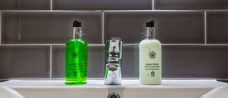 A bathroom sink with three bottles of liquid soap.