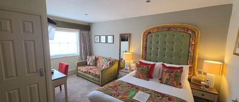 Una habitación de hotel con cama, una silla, un escritorio y una ventana con cortinas.