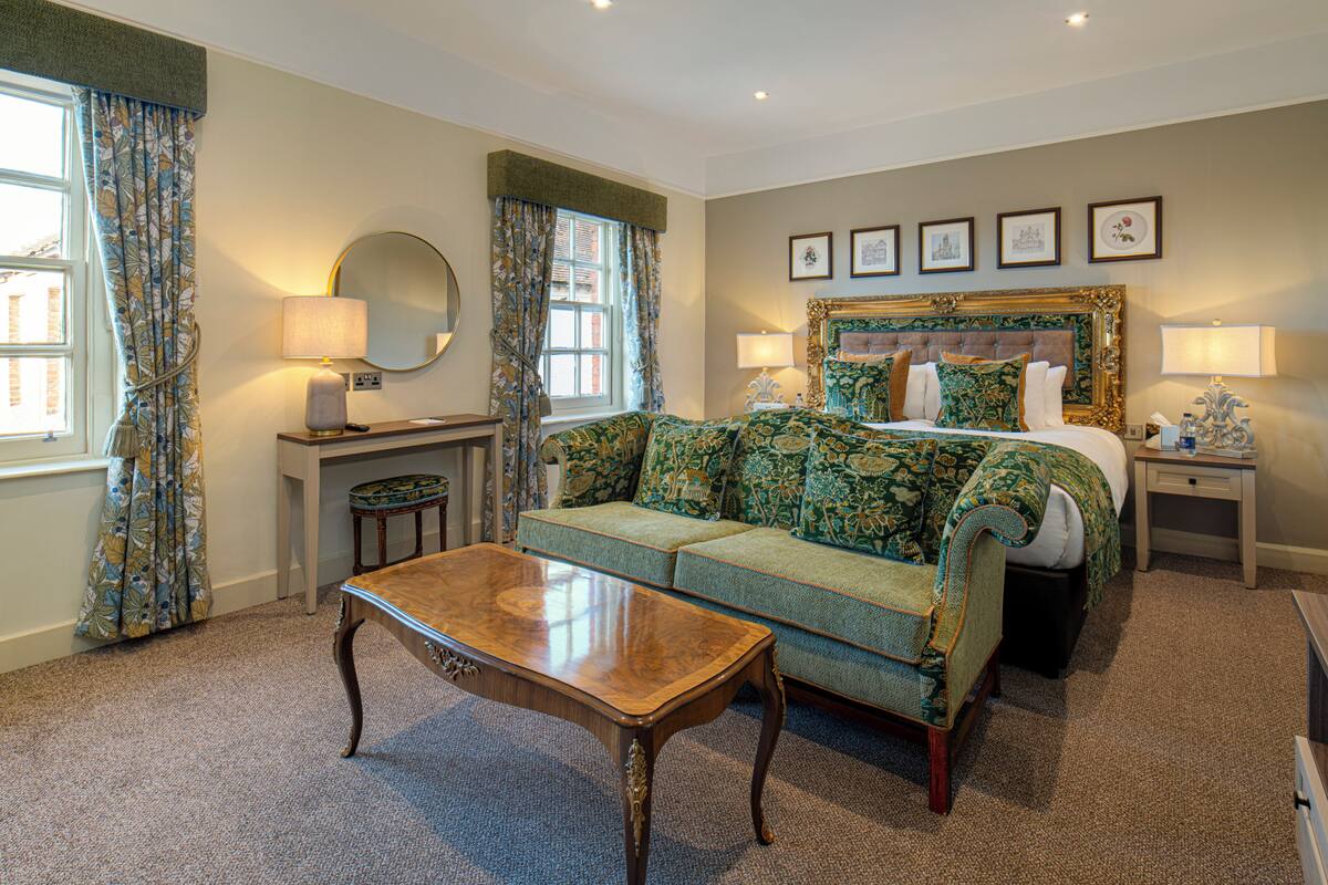 A hotel room with a bed, a sofa, a desk, and a table.