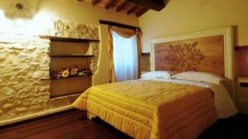 A bedroom with a stone wall, a wooden headboard, and a bed with a yellow bedspread.