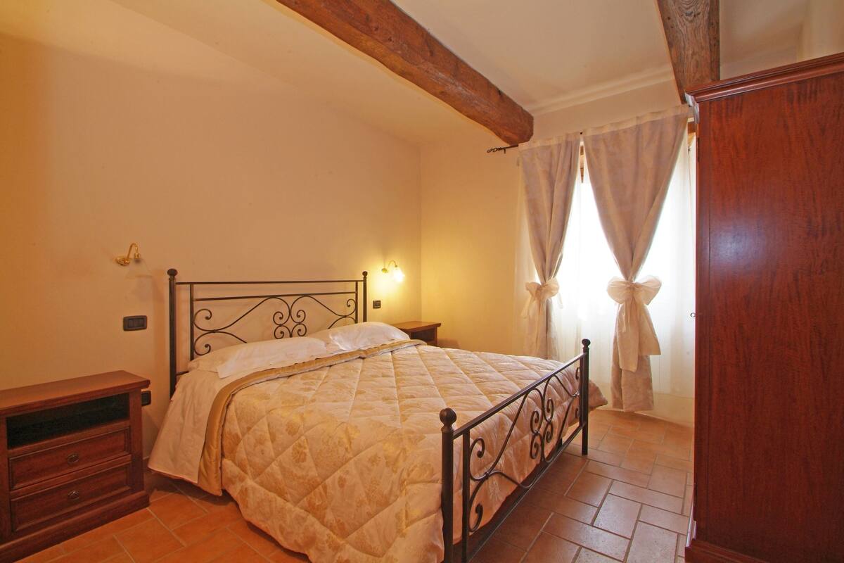 A bedroom with a bed, wooden nightstand, and a wardrobe.