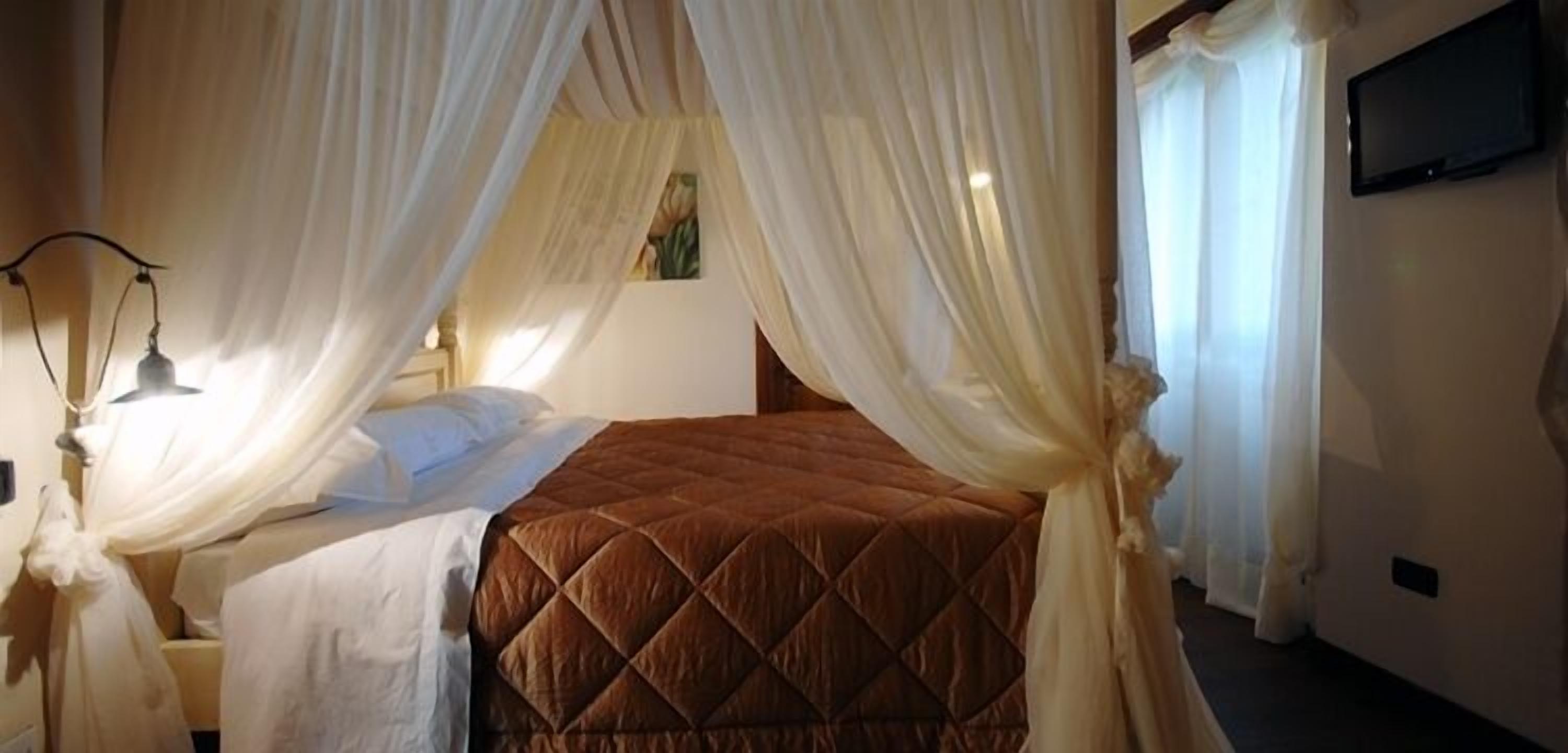 A bedroom with a bed, a bedside table, a lamp, and a television on the wall.