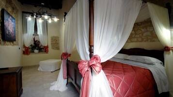 A bedroom with a four-poster bed, a stone wall, and a television on a wooden cabinet.