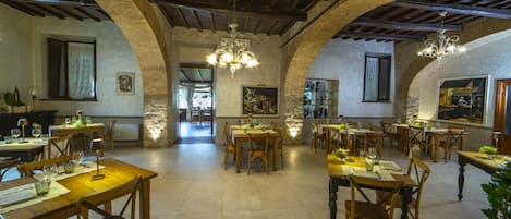 A restaurant with wooden tables and chairs, arched ceilings, and chandeliers.
