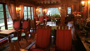A cozy dining area with wooden furniture, checkered curtains, and a view of the outdoors. - Villa Anna Maria (Ayas)
