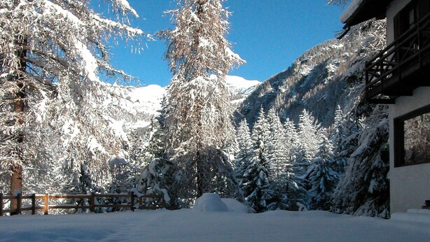 A snow-covered mountain landscape with a wooden fence and a building with large windows. - Villa Anna Maria (Ayas)