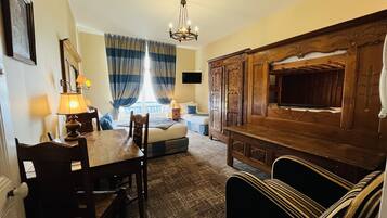 Una habitación de hotel con una cama de madera, un escritorio con lámpara, un televisor y un armario de madera grande.