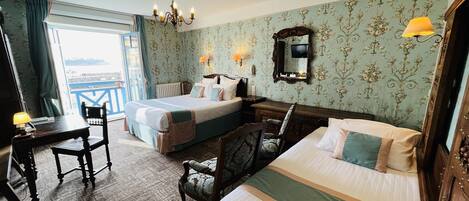 Una habitación de hotel con cama, escritorio, silla, cómoda y candelabro.