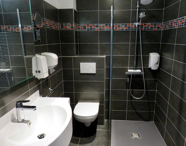 A modern bathroom with a white sink, toilet, and shower. - Logis Hôtel Restaurant le Printania (Dinard)