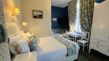 Une chambre d’hôtel équipée d’un lit, d’un bureau, d’une chaise, d’une télévision et d’une armoire.
