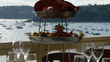 A seafood platter on a metal stand with a view of boats on the water.