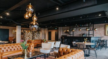 Un área de lounge moderna con sofás de cuero, un bar y una pared de ladrillo.