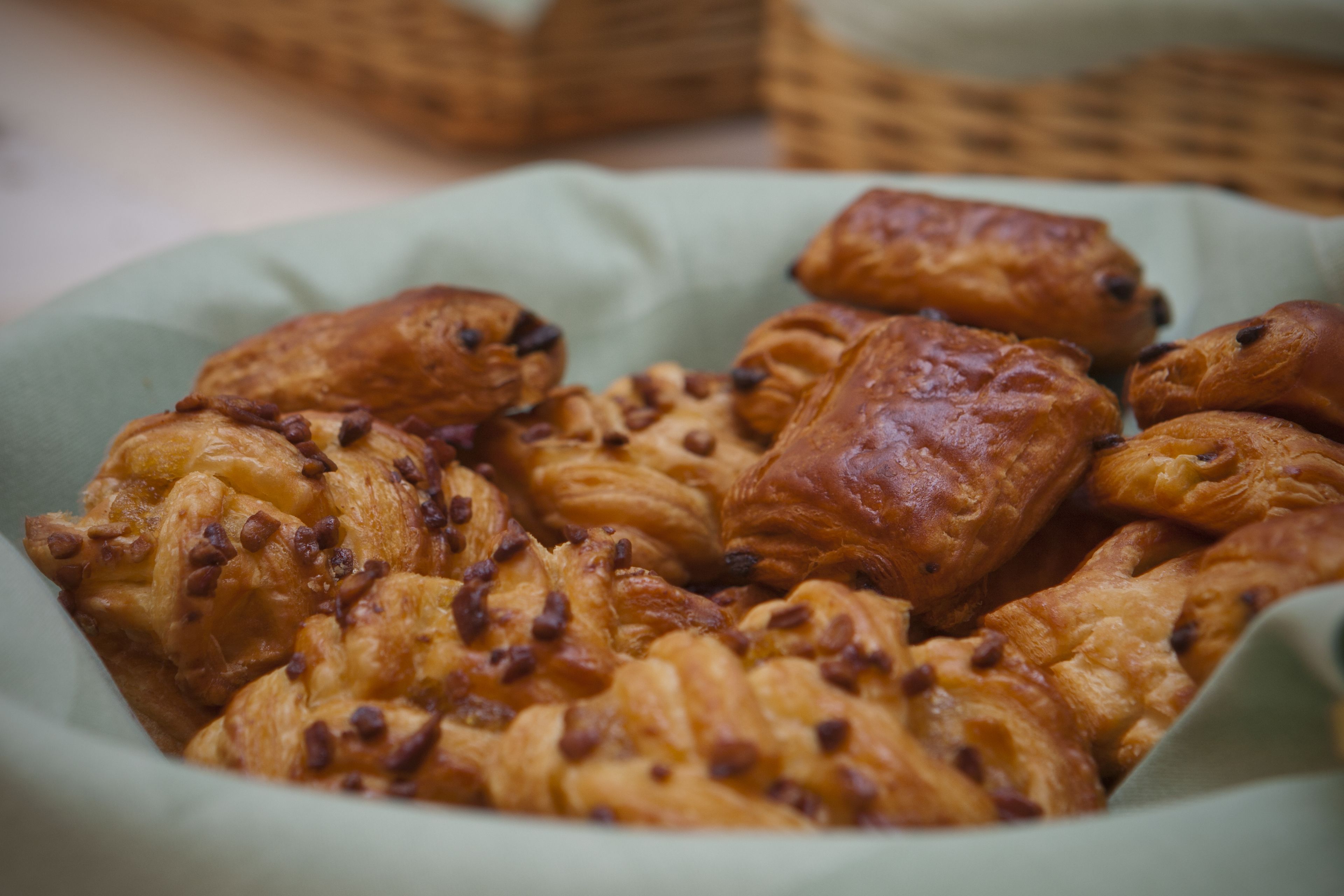 Una cesta repleta de diversos pasteles, entre ellos, croissants y bollos con chips de chocolate.