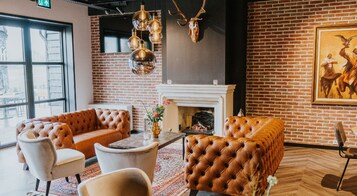 Un espacio lounge moderno con sofás de cuero, chimenea y pared de ladrillo.