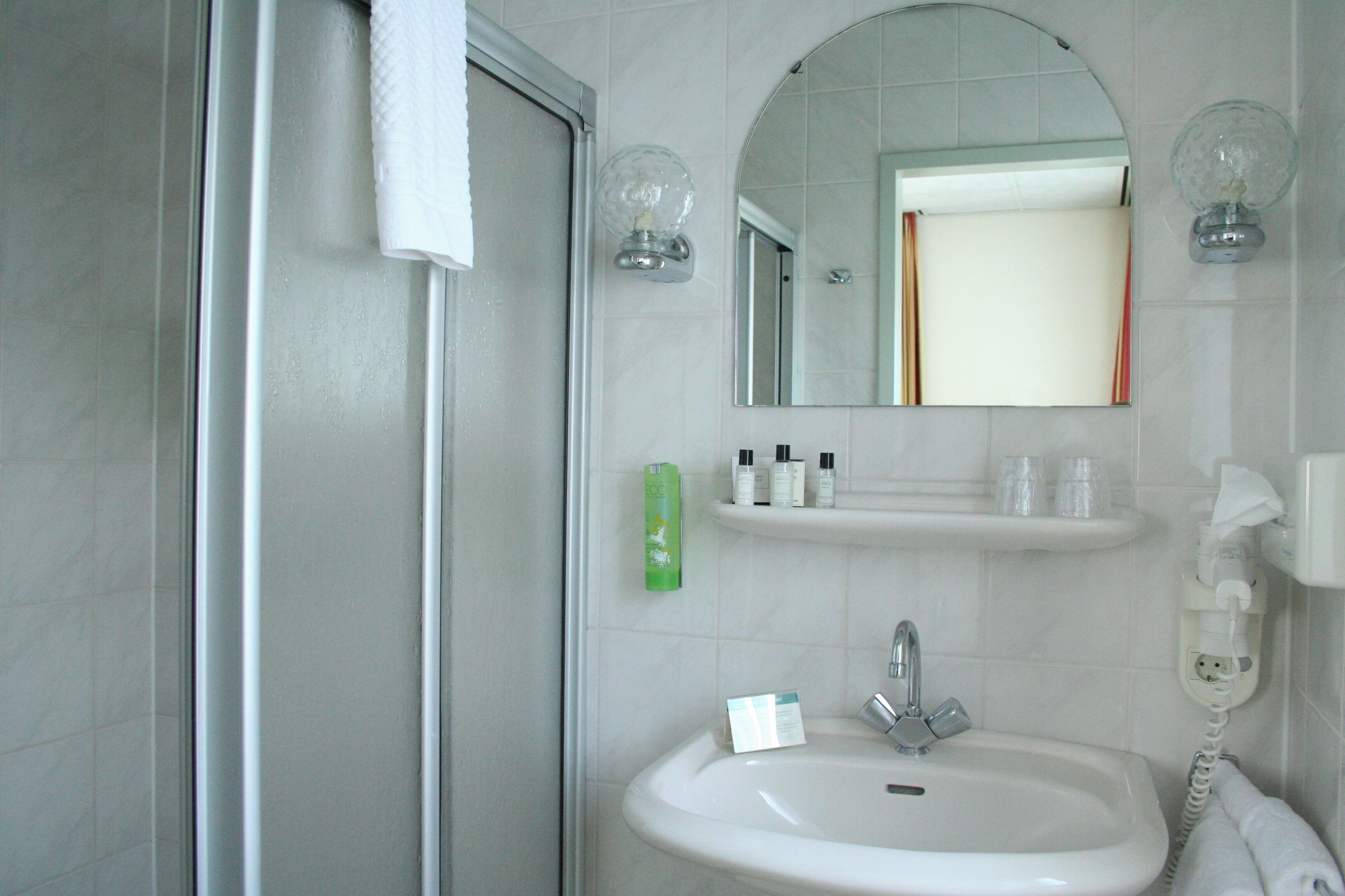 A bathroom with a white sink, a mirror, and a glass shower enclosure.