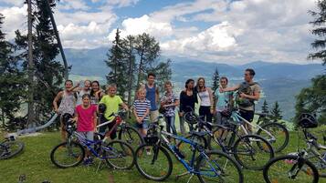 Een groep mensen met fietsen op een grasheuvel, met uitzicht op een berg in de verte.