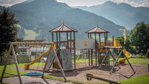 Un parque infantil con toboganes y estructuras para escalar, con montañas al fondo.