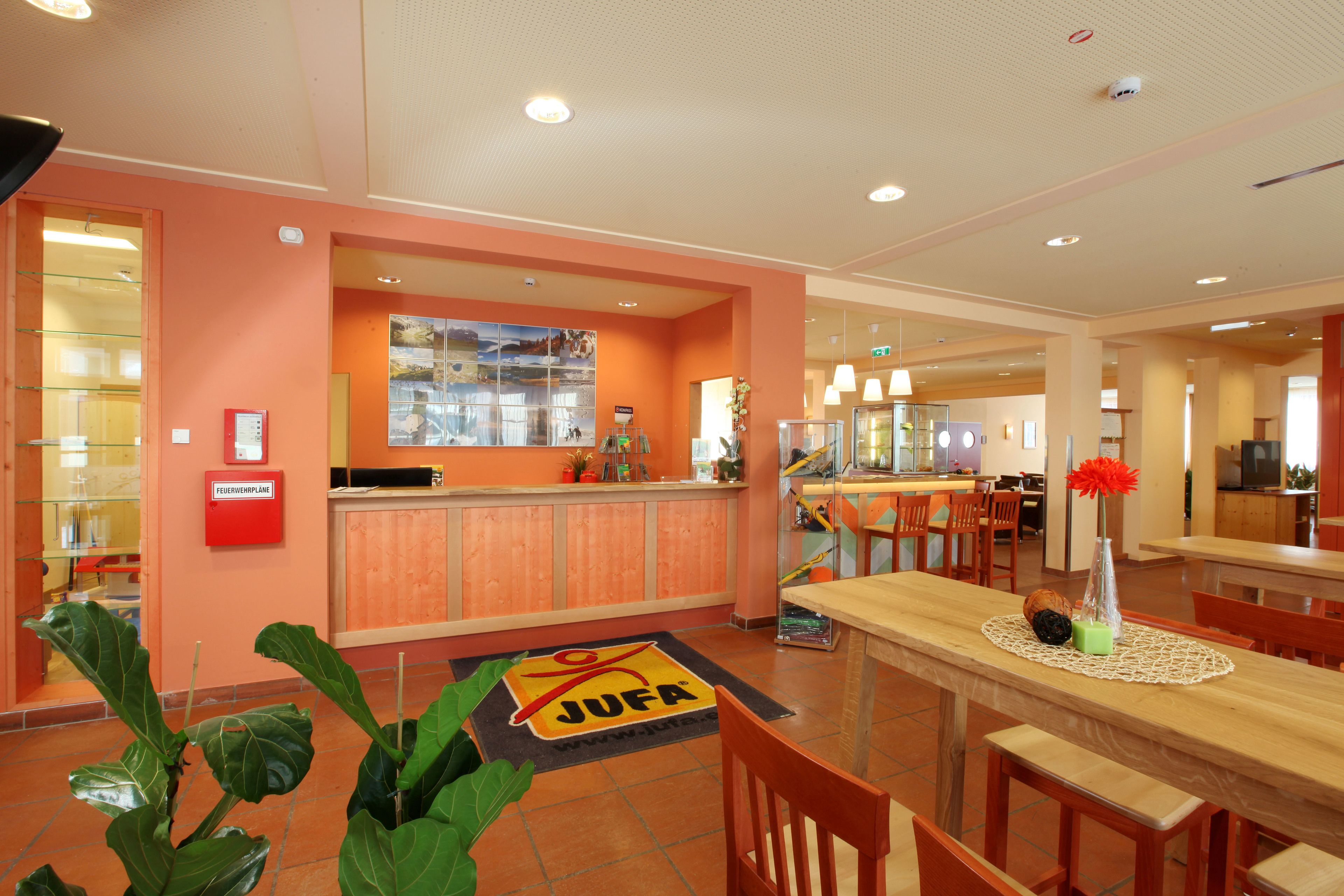 A hotel lobby with a reception desk, seating area, and a large window.