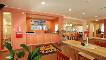 A hotel lobby with a reception desk, seating area, and a large window.
