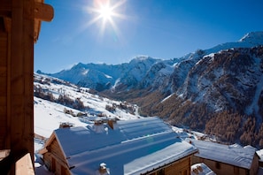 A wooden cabin with a snow-covered roof, surrounded by snow-covered mountains and a clear sky. - Hotel & Spa L'Alta Peyra (Saint-Veran)