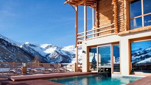 A pool area with lounge chairs, a wooden deck, and a mountain view. - Hotel & Spa L'Alta Peyra (Saint-Veran)