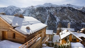 A wooden chalet with a snow-covered roof, set against a backdrop of snow-capped mountains and a clear sky. - Hotel & Spa L'Alta Peyra (Saint-Veran)