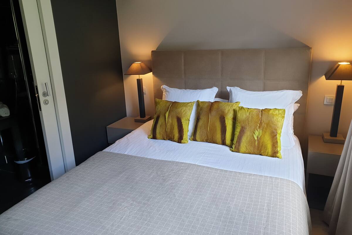 A hotel room with a large bed, two bedside lamps, and a headboard.