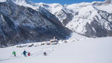 Un paysage de montagne enneigé, avec des skieurs dévalant une pente.