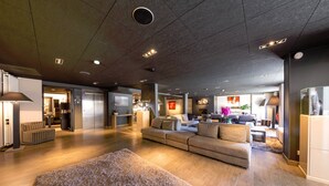 A spacious living area with a large sofa, a fluffy rug, and a kitchen in the background. - Hotel & Spa L'Alta Peyra (Saint-Veran)