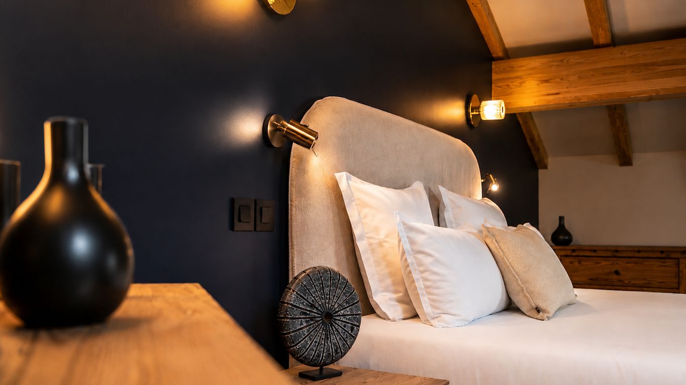Ein Schlafzimmer mit einem Bett, Kissen, einer Vase und Wandleuchten.