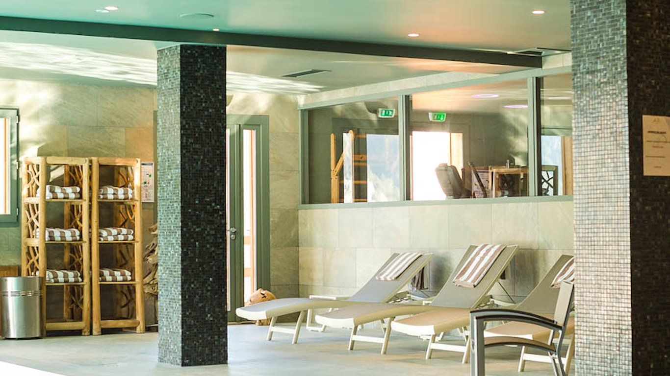 A waiting area with lounge chairs, a wooden chair rack, and a tiled wall.