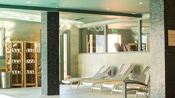 A waiting area with lounge chairs, a wooden chair rack, and a tiled wall.