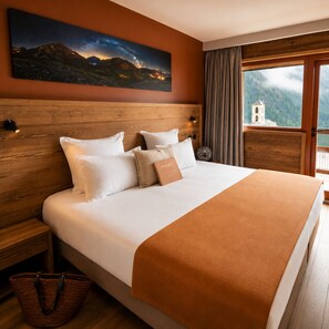 A hotel room with a large bed, wooden headboard, a night sky mural, a view of mountains, and a window with curtains. - Hotel & Spa L'Alta Peyra (Saint-Veran)