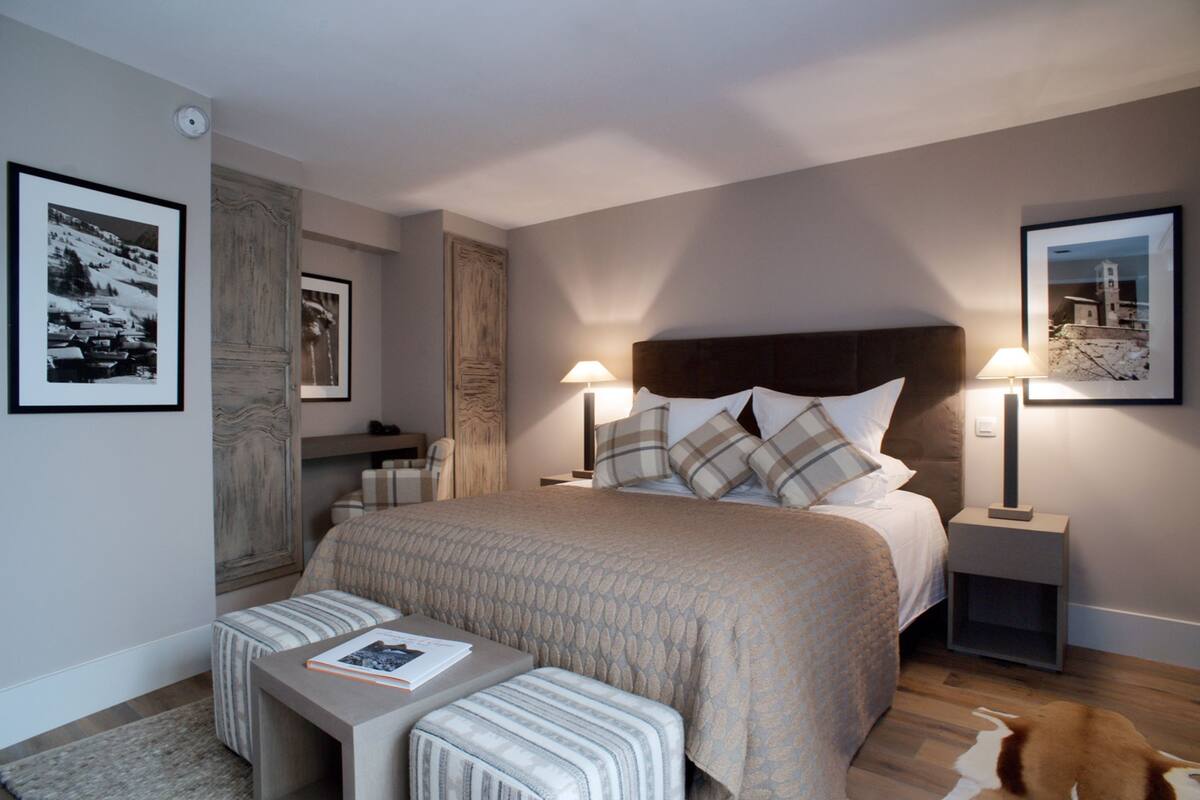 A modern hotel room with a large bed, two bedside tables, a small sofa, and a rug.